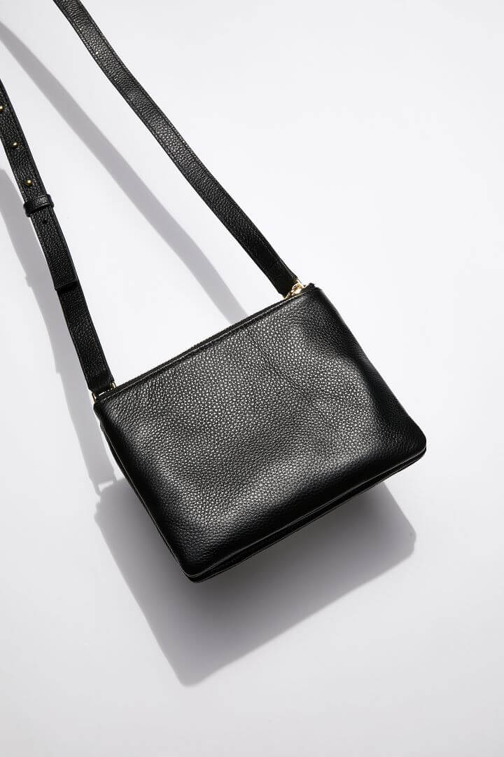 front view of MON Purses' double pouch bag in black pebbled leather with gold hardware with the long shoulder strap 