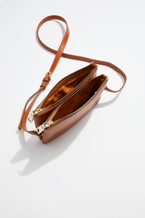 interior view of mon purses' double pouch bag in camel pebbled leather with gold hardware with long shoulder strap showing interior of both the pouches