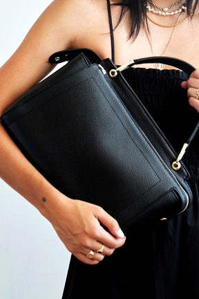 model holding mon purses black pebbled leather Day Tote Bag with gold hardware 
