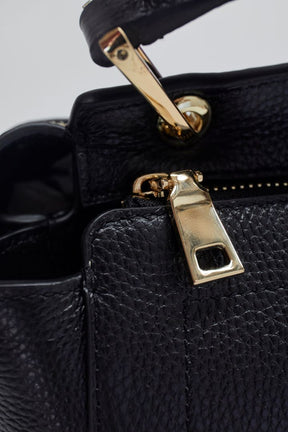 close up of gold zip detailing of mon purses black pebbled leather Day Tote Bag with gold hardware 