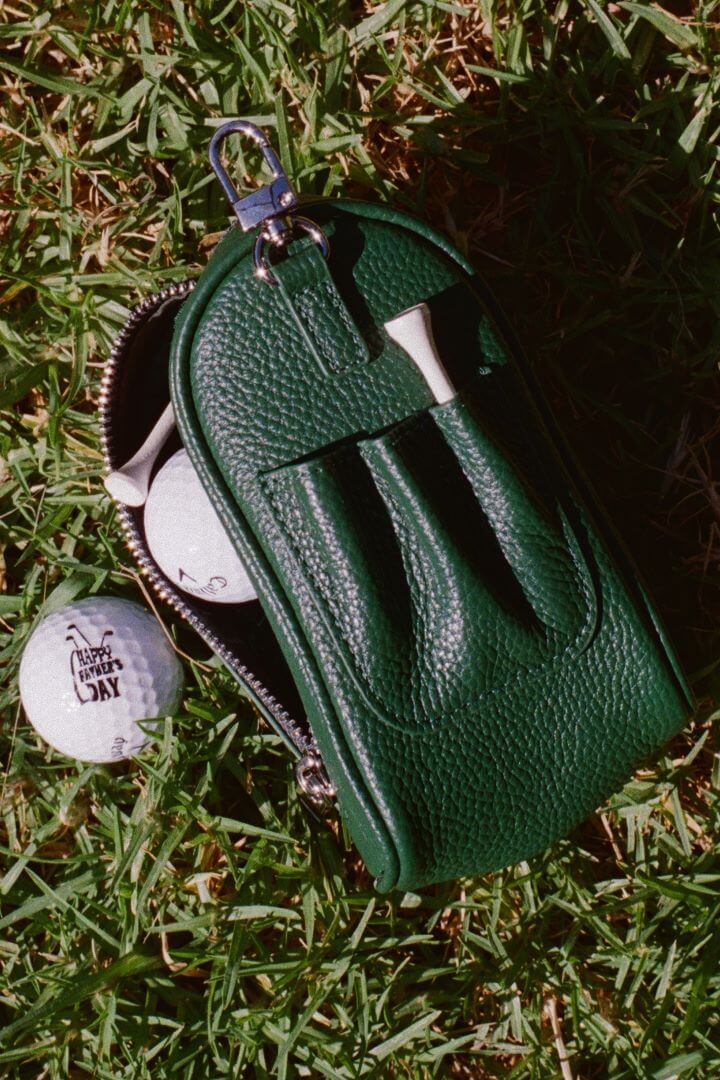 back view of mon purses' dark green pebbled leather golf ball pocket showing the pocket in use with tees placed in the tee pockets and golf balls enclosed